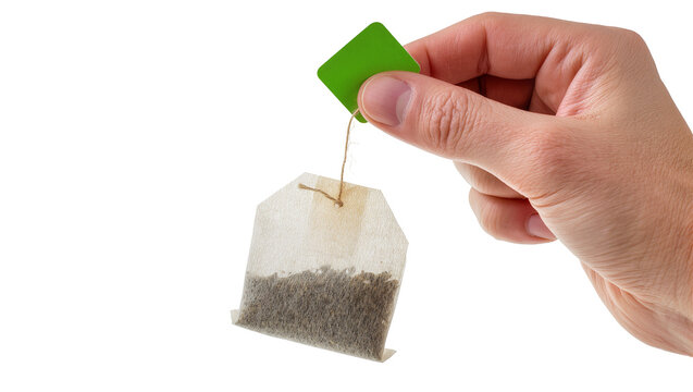 Isolated human hand gently holding a tea bag by its vibrant green tag, ready for brewing.