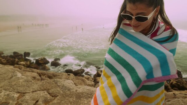 Cozy seaside snapshot of woman with windblown hair and sunglasses