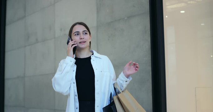 Woman with bag considers choice. Customer pauses during shopping to select item attentively. Woman during shopping break carefully contemplating her purchase outside boutique entrance