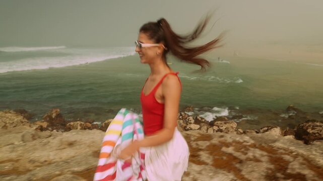 Spectator captures woman flipping towel near shoreline rocks