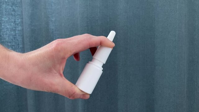 The woman presses on the nasal spray bottle. A compact and convenient nasal care product. Spray to facilitate breathing, moisten the mucous membrane and relieve congestion in case of cold or allergy