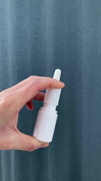 Vertical video. The woman presses on the nasal spray bottle. The spray mechanism allows the solution to be evenly distributed inside the nasal passages. Health care procedure, breathing relief