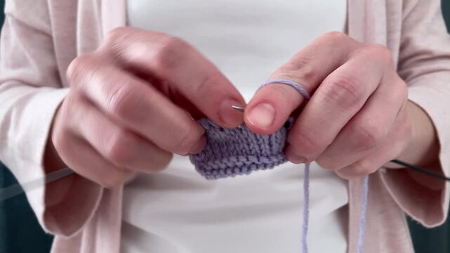 A woman is knitting, creating a unique product with her own hands. Knitting as a way of self-expression, skill development and creation of cozy author's things with soul and attention to detail