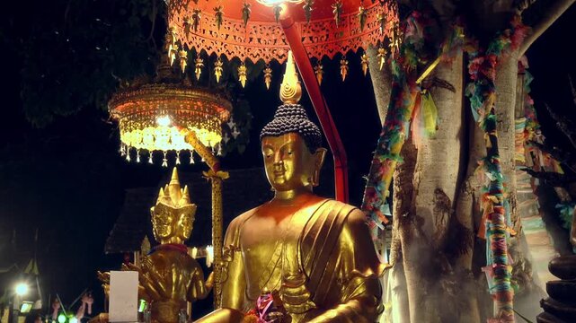 Gilded brass meditating Buddha in Dhyana mudra, red lacquered Chatra canopy, glowing lantern and sacred tree at night, serene devotional atmosphere Wat lok moli temple chiang mai