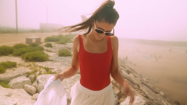 Confident summer model. Fashionable woman enjoys windy coastal scene
