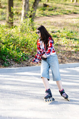 Fototapeta premium Young woman roller skating in a park during spring enjoying a sunny day