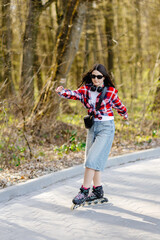 Fototapeta premium Young woman roller skating in a park during spring enjoying a sunny day