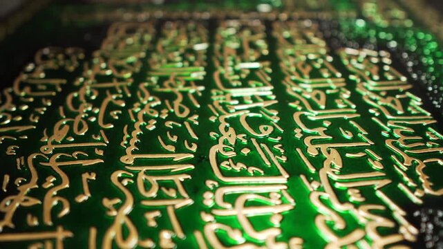 Close up cinematic footage of ornate Arabic calligraphy on a green textured surface.