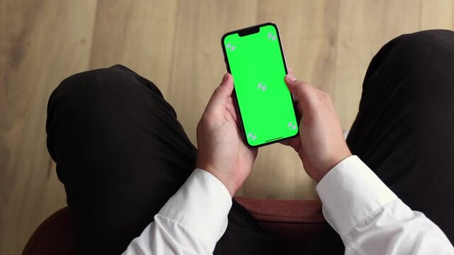 Smartphone with Green Screen Mockup. Close-up of a person using a smartphone with green screen for mobile app or website interface replacement.