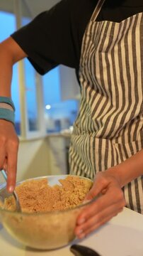 Individual mixes crumb components in glass bowl on kitchen counter