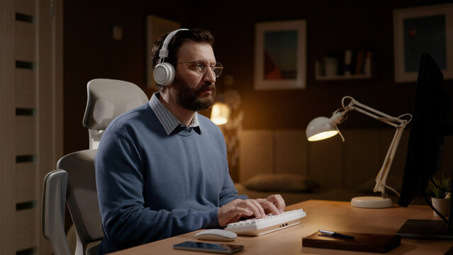 Man wearing headphones works at computer