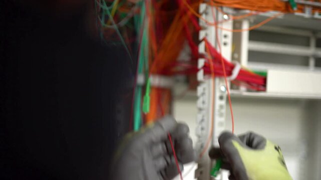 Person working with colorful wires and connectors in a server room environment