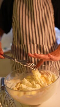 Detailed view of hands checking batter texture under cozy lighting
