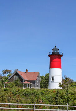 Nauset Light stands above the coastal landscape in Eastham, Massachusetts. The iconic red and white lighthouse and keeper&rsquo;s house are Cape Cod landmarks.