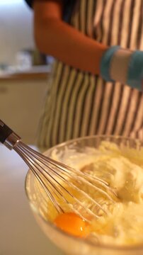 Egg yolk blending into airy batter while whisking rapidly