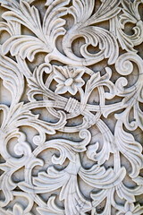Close up of an intricate white marble relief featuring floral motifs and scrolling ornamental patterns. Architectural detail showcasing craftsmanship and decorative design. © Ryan