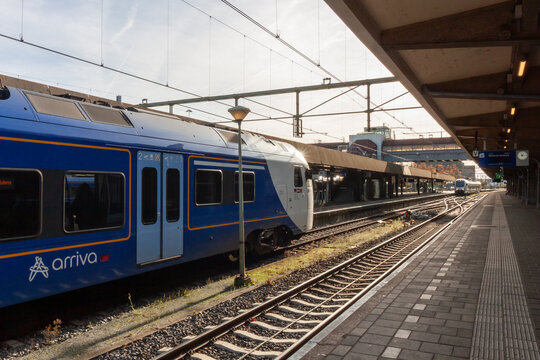 Blue regional passenger train standing at the platform of Maastricht railway station in sunny weather