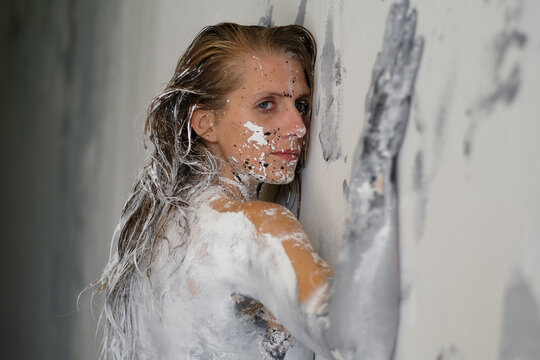A woman covered in white and black paint presses against a wall creating an expressive body art portrait that explores emotion creativity transformation and human connection.