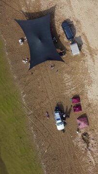 Top down aerial view of large camping tent and off-road cars on sandy river beach, adventure lifestyle, Syr Darya, Kazakhstan. High quality 4k footage