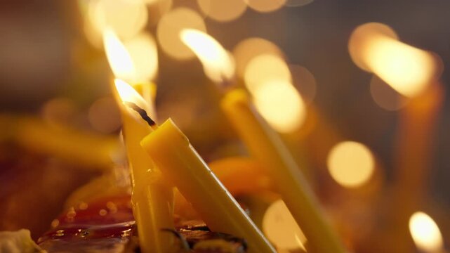 
A close-up image of a fallen candle struggling to emit light and melting, with a bokeh effect of lights in the background, conveys a sense of struggle to survive in the heat.