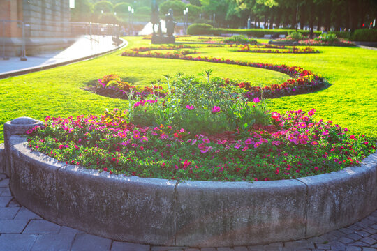 Central urban park in Oslo features manicured green lawns and curving stone flowerbeds filled with vibrant pink blooms. Beautifully landscaped public garden offers a peaceful escape in Oslo city