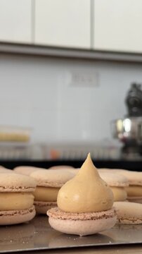 Detailed macro shot of salted caramel ganache piped onto French macaron shells during confectionery production