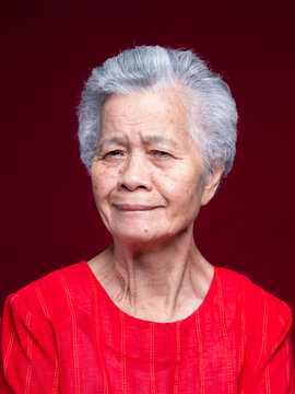 Senior woman portrait in red blouse on dark red background