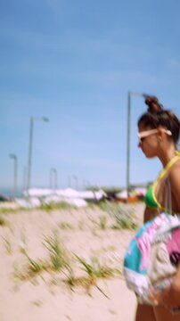 Woman walking across a sandy beach dune in sunlight