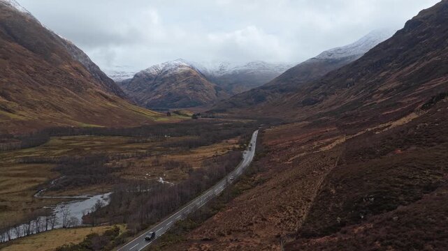 Aerial view of cars driving through glencoe valley in scotland