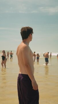 Young man standing in shallow sea water on a sunny beach