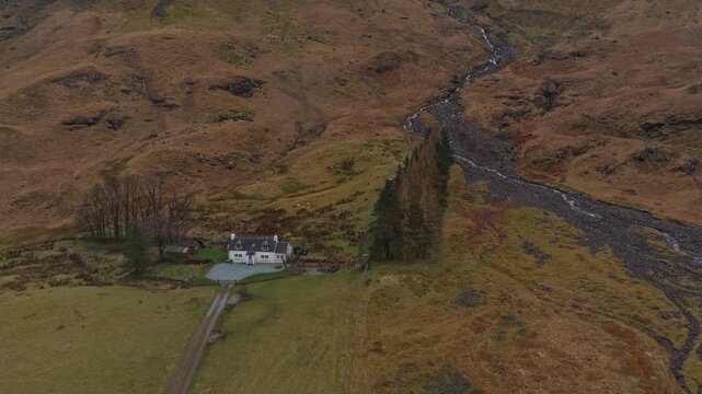 Drone flying backwards from secluded house in glencoe valley scotland