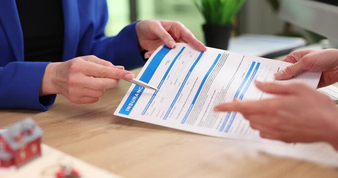 Woman doctor presents medical document during office consultation. Specialist points at form guiding patient through important health details