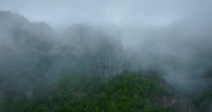 Low clouds conceal rocky Appalachian peaks above green forest canopy, aerial medium tracking left