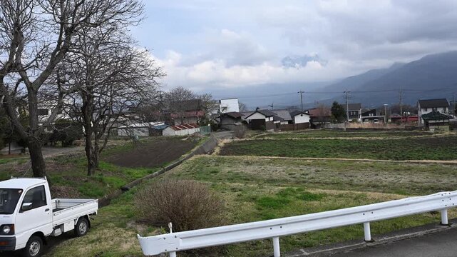 散歩道から望む雄大な南アルプスの山並みと軽トラが停まるのどかな田園風景