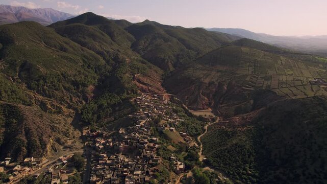 Ourika Valley near Marrakech, Marrakesh Safi, Morocco, featuring Berber mountain villages, terraced agriculture, Mediterranean shrubland and eroded High Atlas foothills, drone parallax pullback orbit