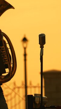 Microphone instrument musician playing brass horn during golden hour sunset performance outdoors at dusk for jazz concert