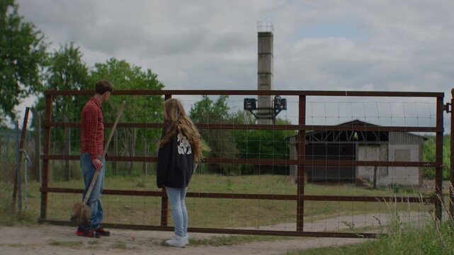 Young friends approach an abandoned farm building with a shovel, suggesting secret digging, poor decision making, risk, trespass and youth behavior themes