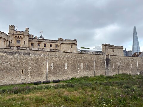 Historic stone castle battlements towering above a green grassy moat area