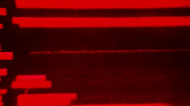 Static shot of red digital glitch lines scrolling across monitor display with horizontal scan in dark studio setting