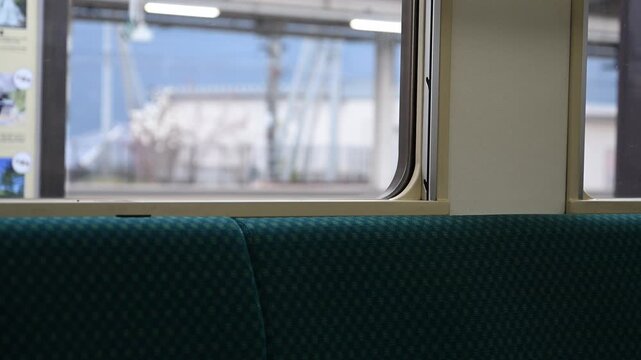 駅に停車中の電車の車内から窓越しに向かいのホームに停まる別の列車を眺める風景