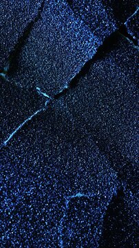 Dark cracked texture slow rotation. Close-up of rough black surface with granular texture and prominent natural cracks. Smooth continuous rotation reveals evolving light reflections.