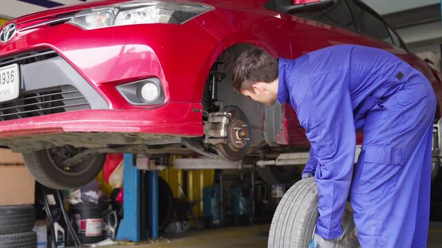 Tire change action by mechanic garage workshop automotive maintenance indoor side view practical skills