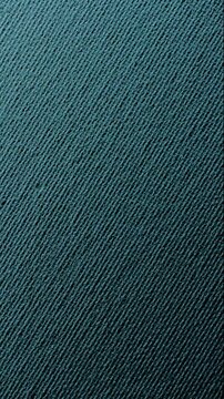  Blue woven texture slow rotation. Close-up of uniform dark teal fabric surface with tight fine weave pattern. Smooth continuous rotation reveals subtle shifts in light and shadow. 