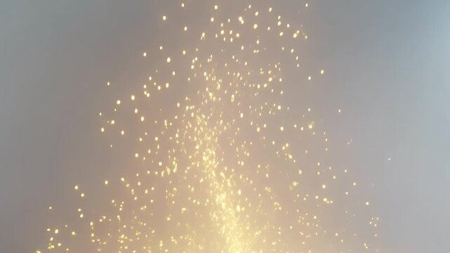 Golden particles erupting upwards in a bright shimmering burst