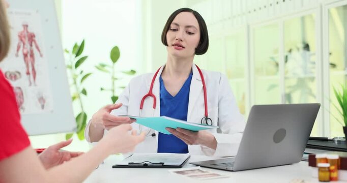 Female doctor accepts patient folder during clinic consultation. Specialist opens file removing X-ray image for careful medical review slow motion