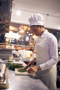 Cook in Professional Modern  kitchen, restaurant concept. female chef preparing prasley