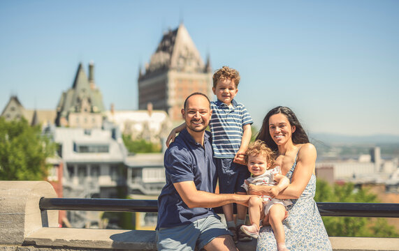 family of four people playing with childs outdoors with chateau frontenac hotel in background
