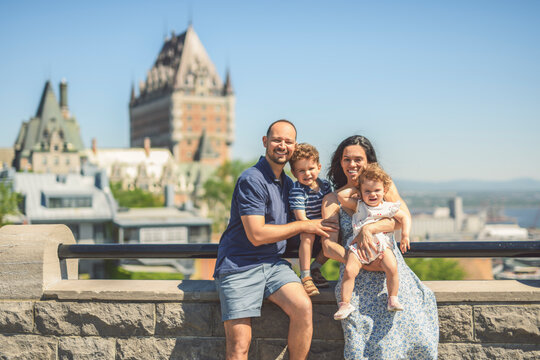 family of four people playing with childs outdoors with chateau frontenac hotel in background