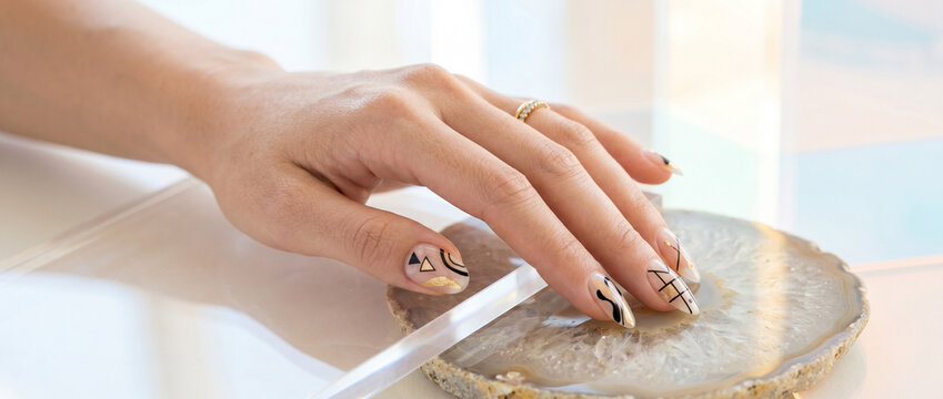 Main de femme avec ongles soign&eacute;s et manucure artistique pos&eacute;e sur une pierre agate