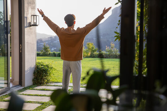 Doorway is opening onto neat lawn with stone path and potted plants, sunlight warming hills